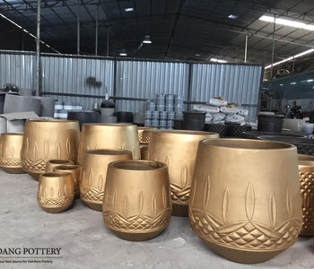 SO IMPRESSIVE: HOANG POTTERY’S COPPER-GOLD PAINTED CEMENT PLANTERS.